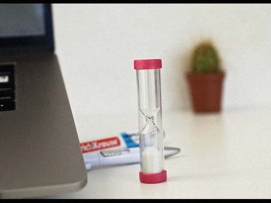 A small egg-timer running down beside a laptop.
